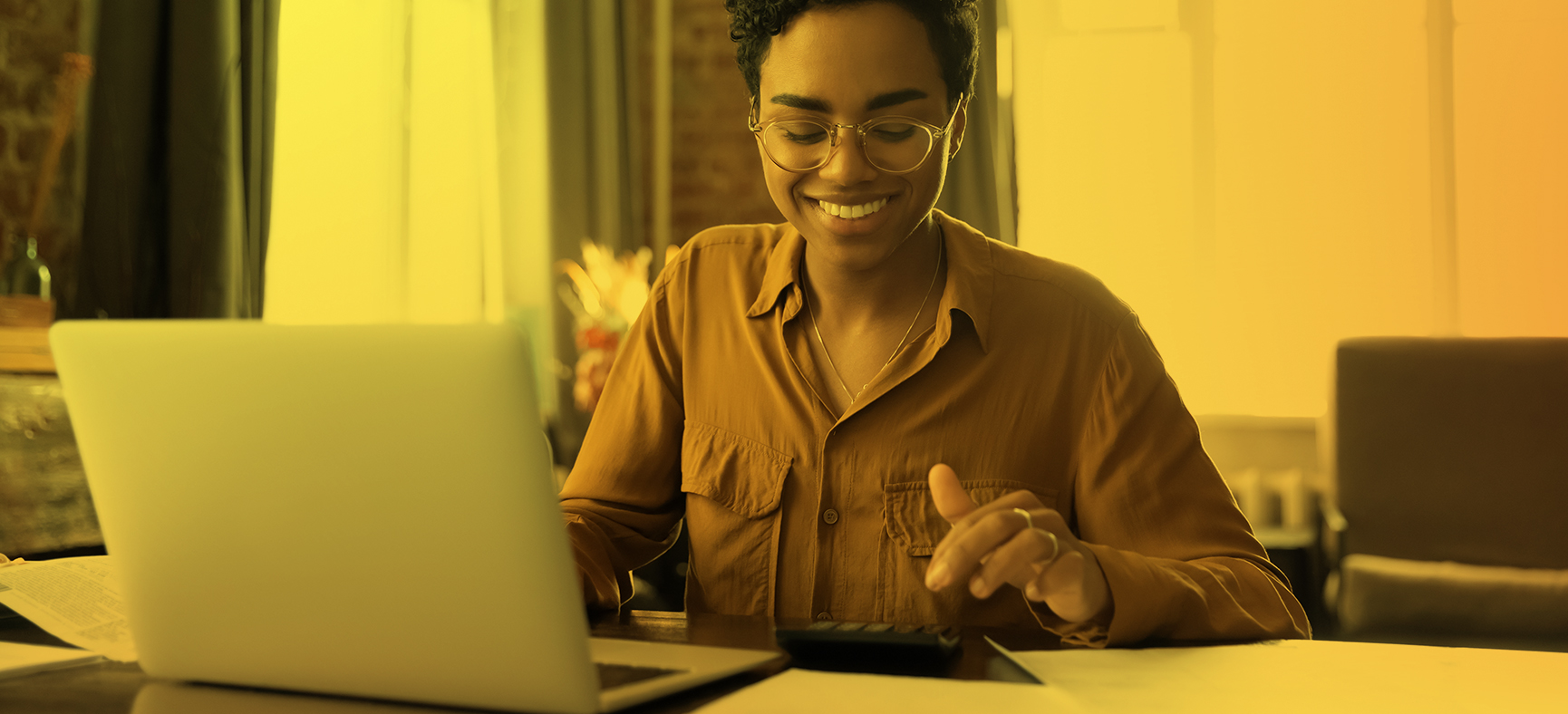 Woman Types at a Calculator Next to Her Computer to Help Her Small Business Get More Business Credit and Funding