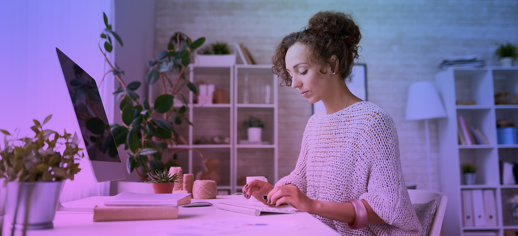 Woman sits at a computer and writes content for her website