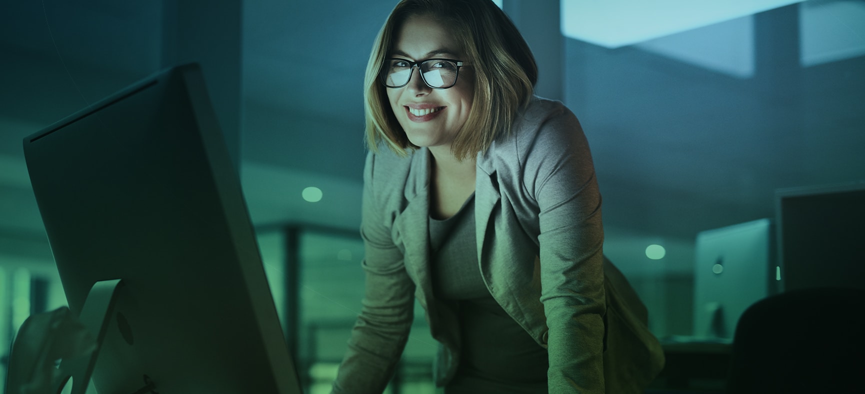 Businesswoman leans on her desk and confidently smiles as she stays in compliance